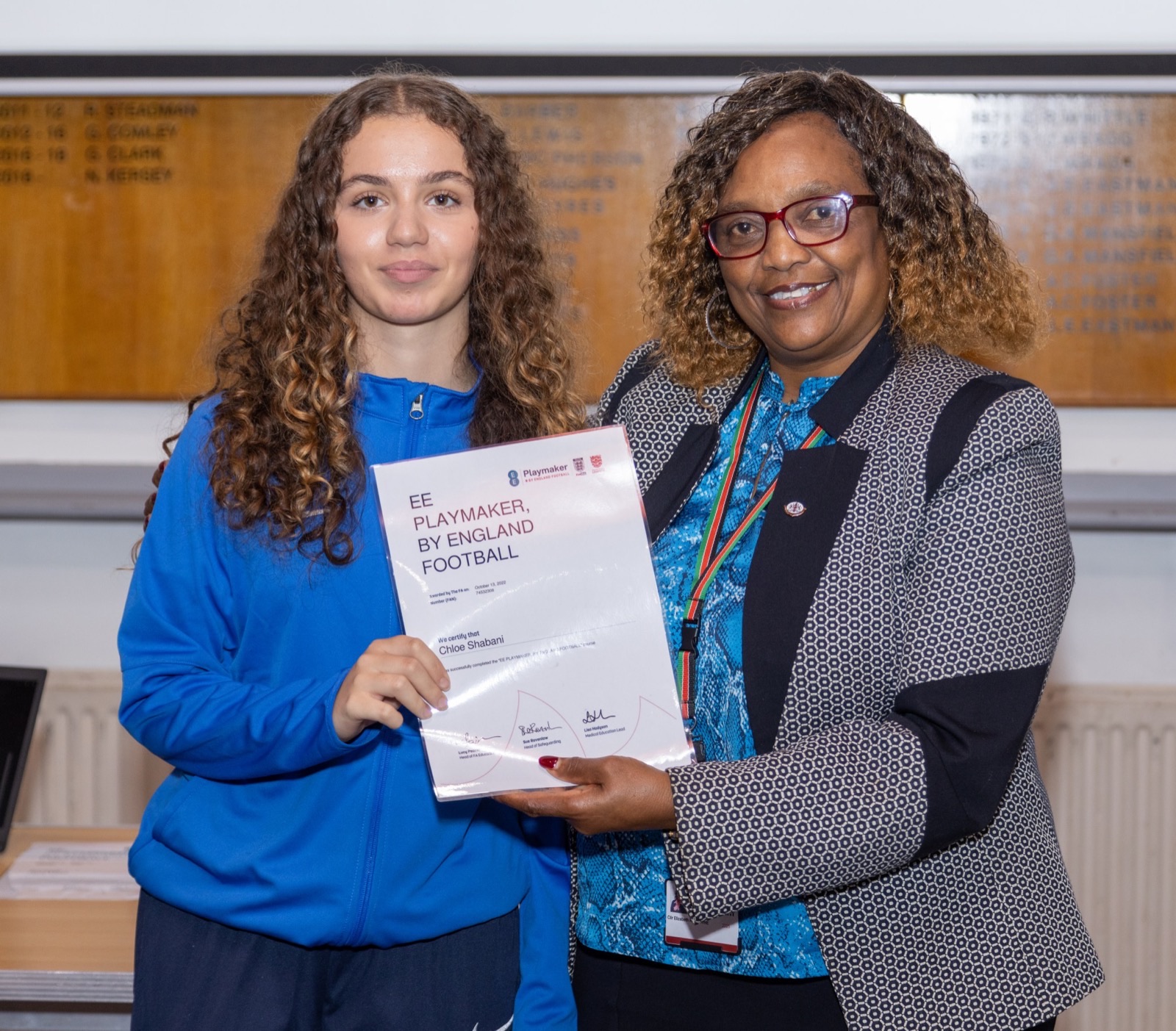 Two students holding certificates of achievement