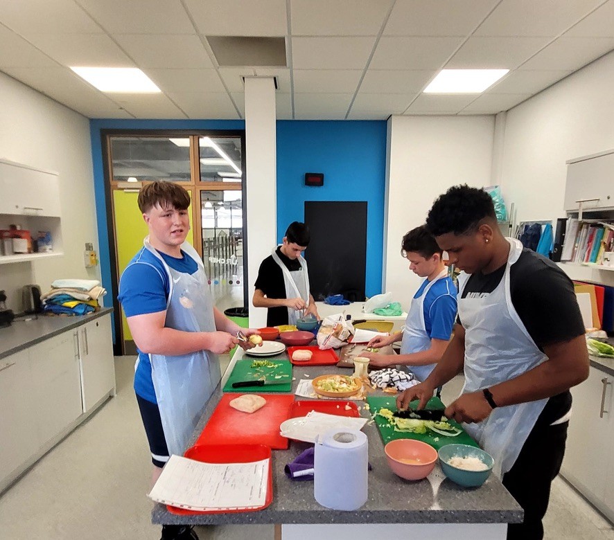 Young people developing practical life skills together in a teaching kitchen