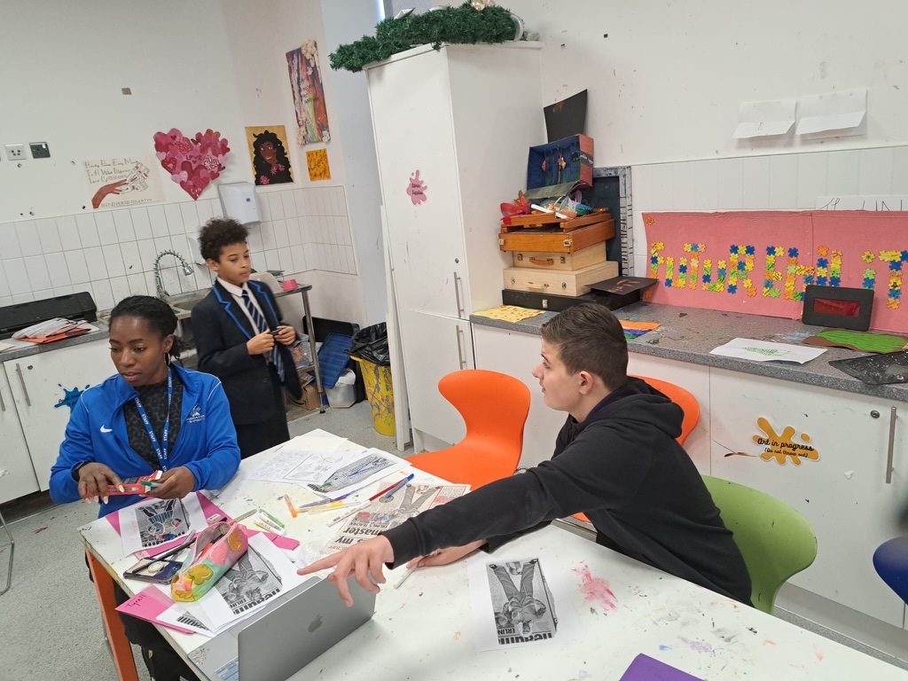 A staff mentor and young people working together at a creative learning table