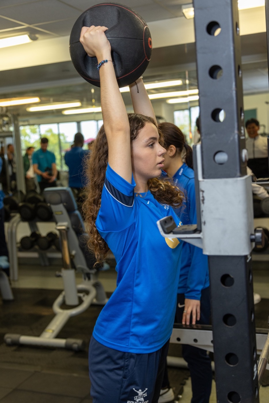 A mentor coaching a student through a weights session in the gym