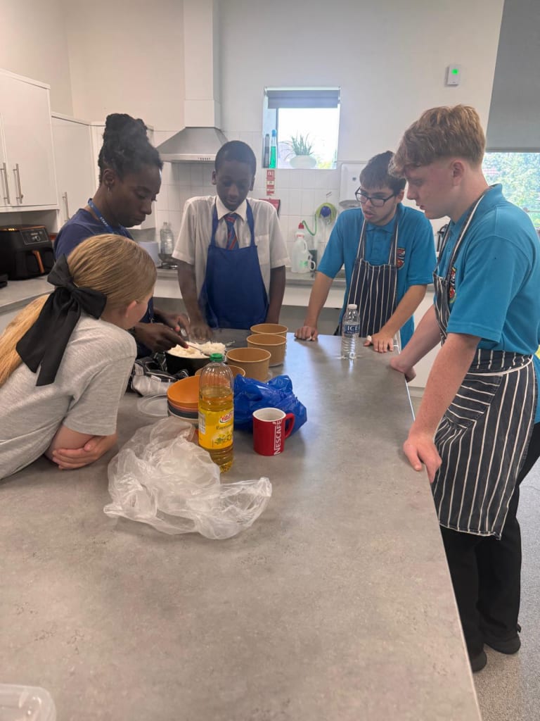 Students and staff learning food preparation together in the teaching kitchen