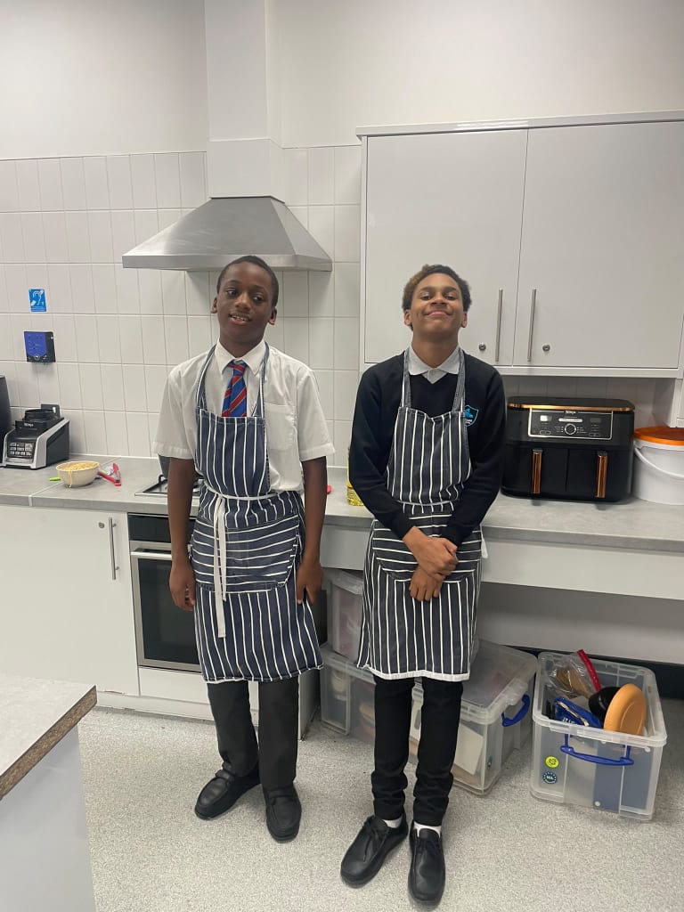 Two students in aprons learning food skills in the teaching kitchen