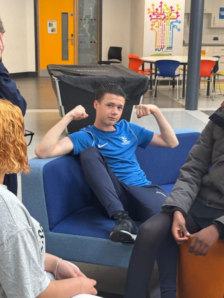 Students relaxing together in the centre lounge beneath the Future wall display