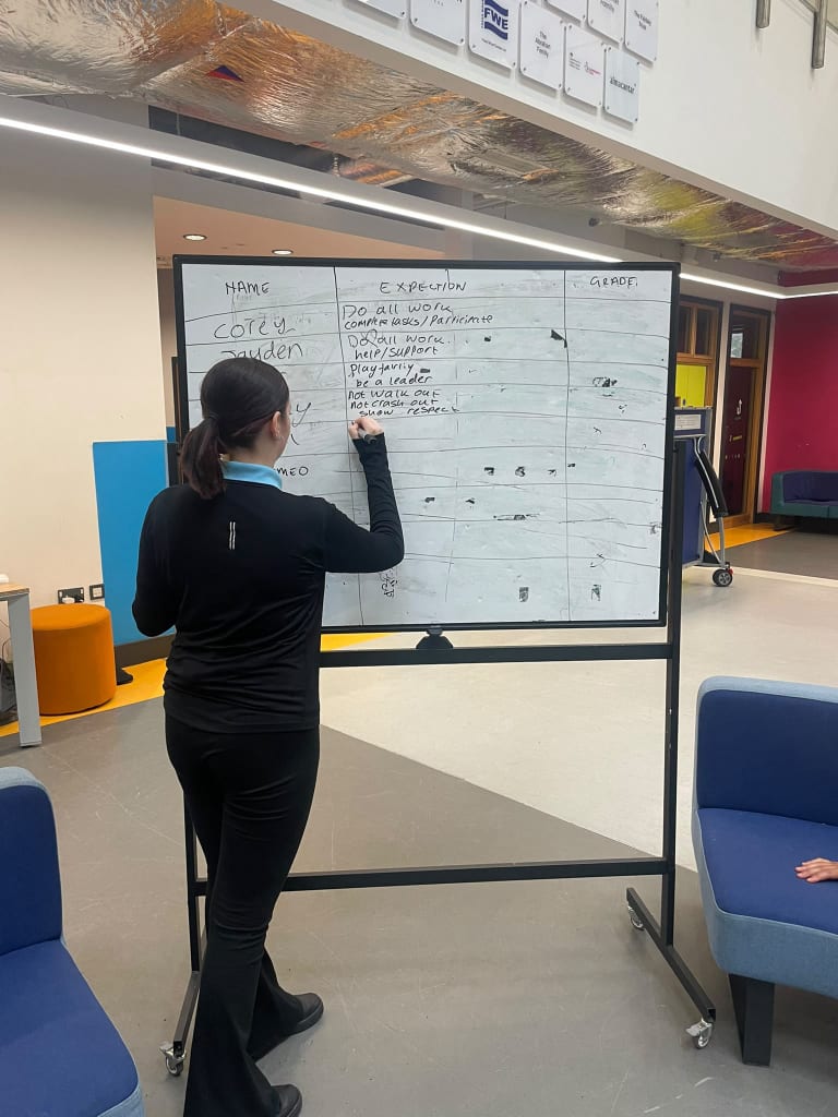 A student writing positive expectations on a whiteboard in the student lounge